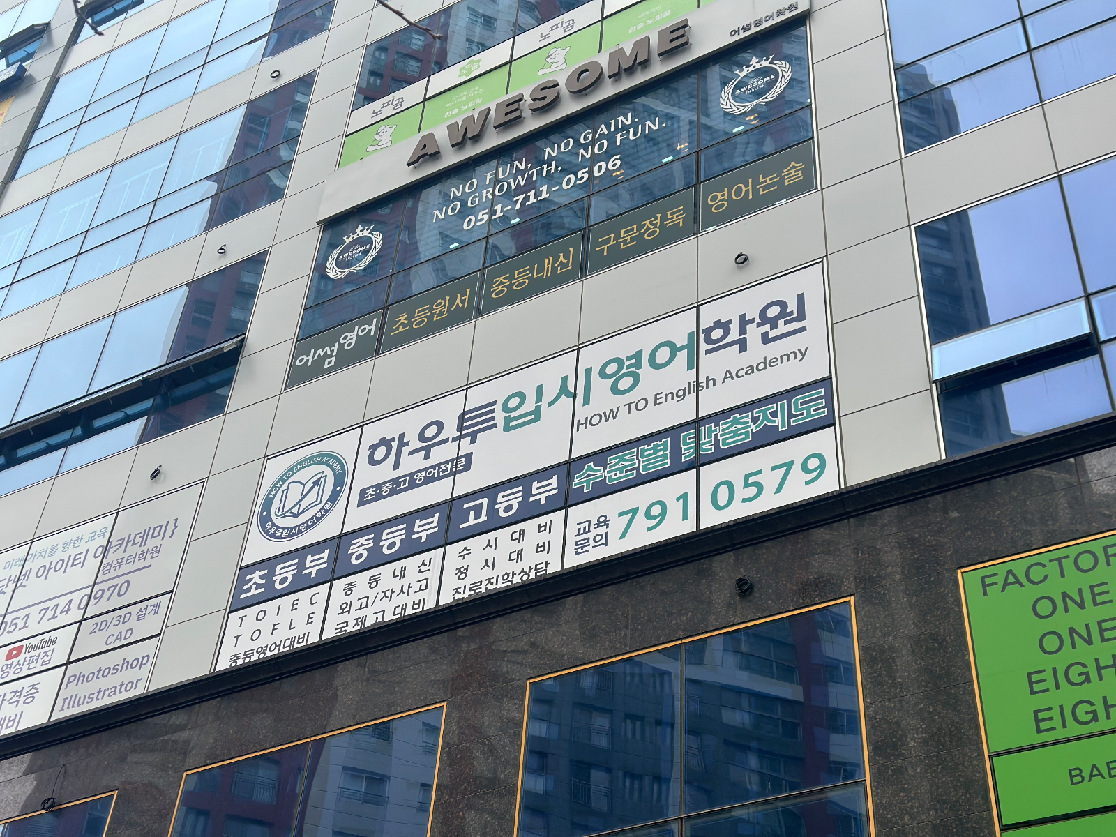 건물 외벽 상단에 붙은 하우투입시영어학원 유리면 광고와 위층 어썸영어 간판