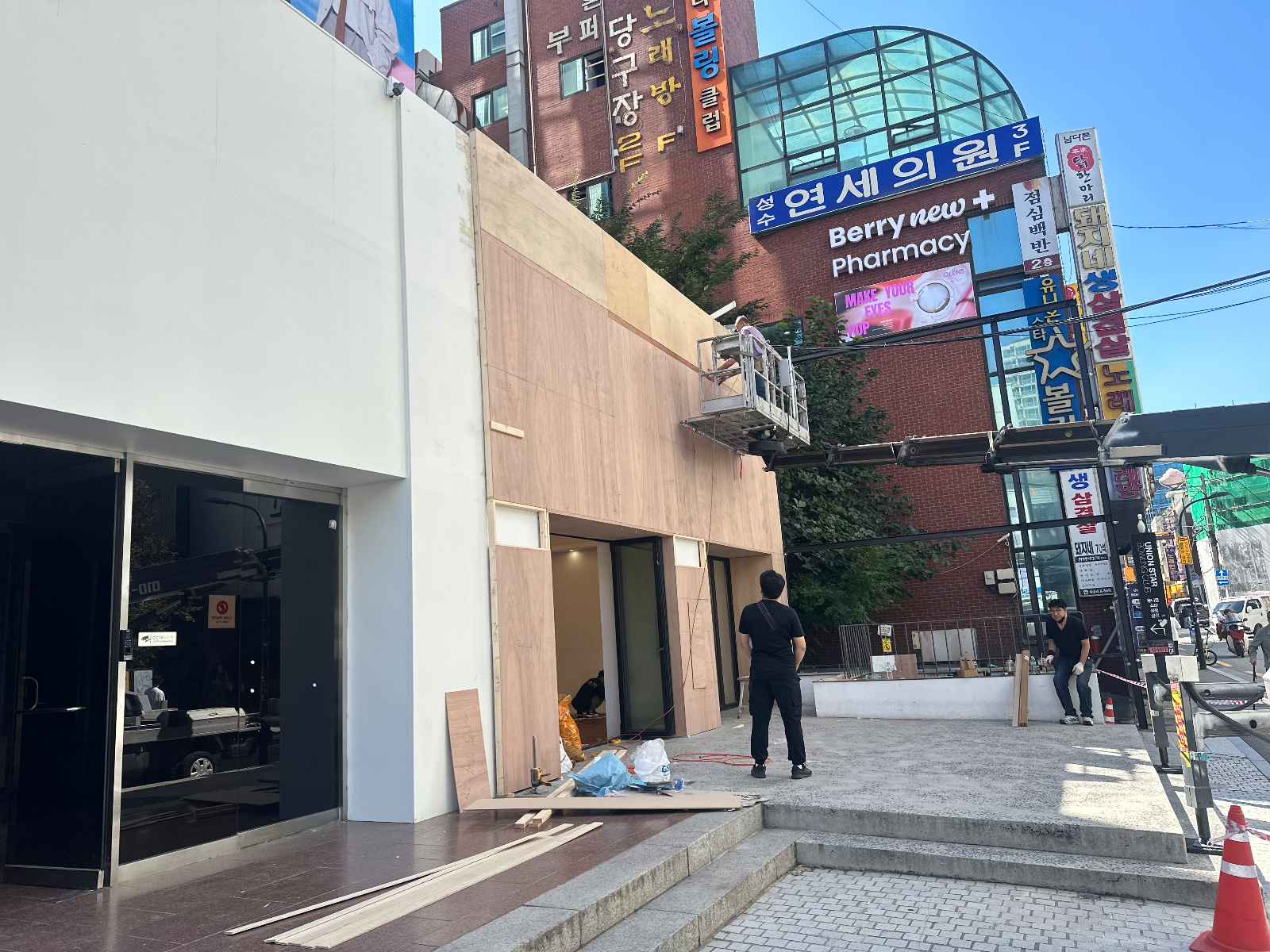 합판으로 덮인 외벽과 스카이 작업대에 올라간 작업자