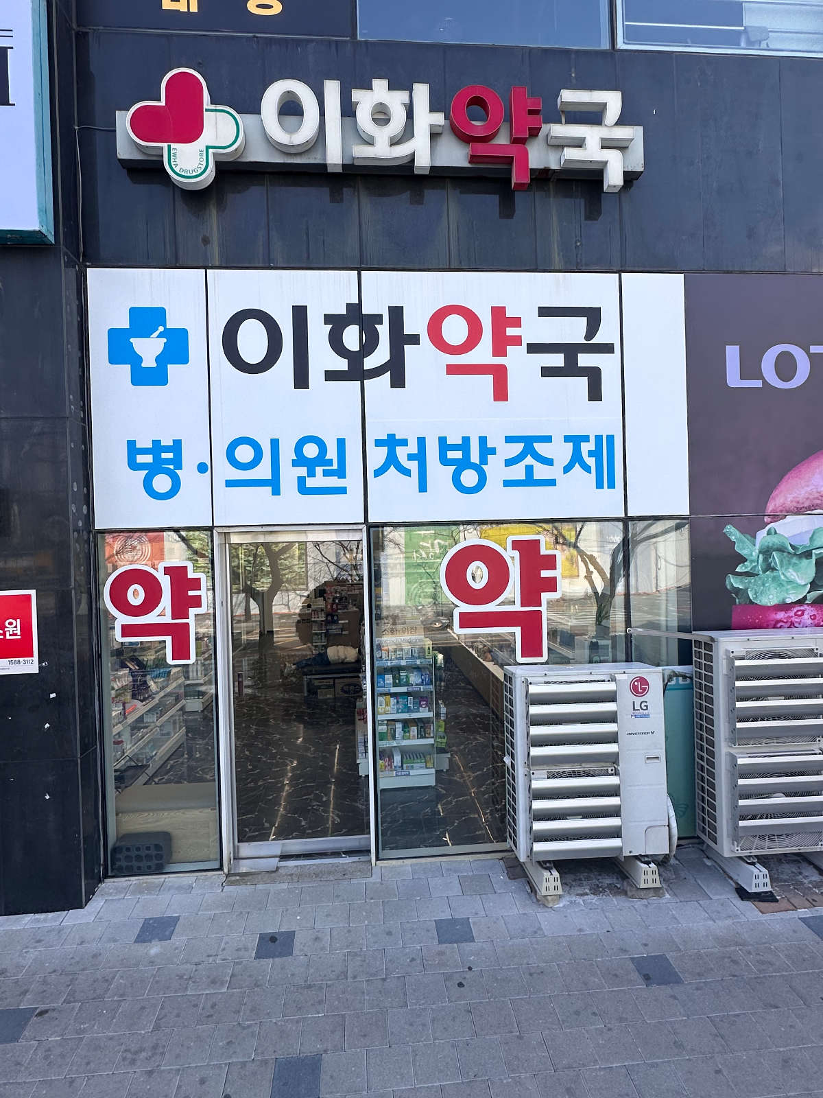 교체 전 이화약국 외관. 상단 채널 간판과 유리창에 붙은 흰 바탕 시트지, 붉은 '약' 글자