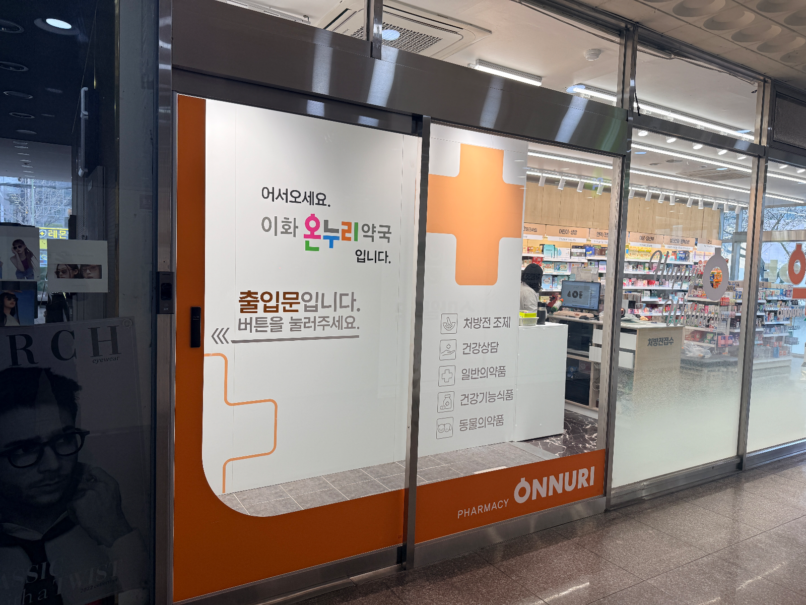 복도 쪽에서 본 자동문 시트지와 열린 유리 너머 계산대