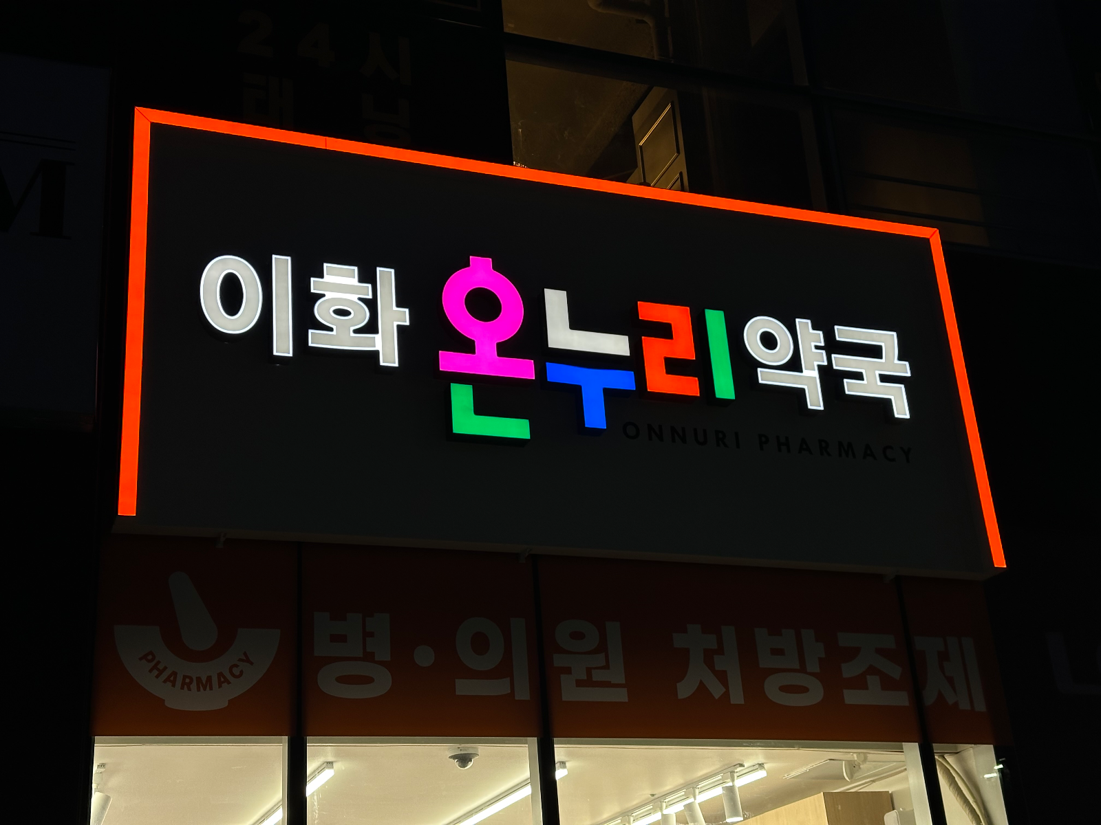 정면에서 촬영한 야간 점등 간판. 검게 보이는 바탕 위로 컬러 글자가 떠 보임