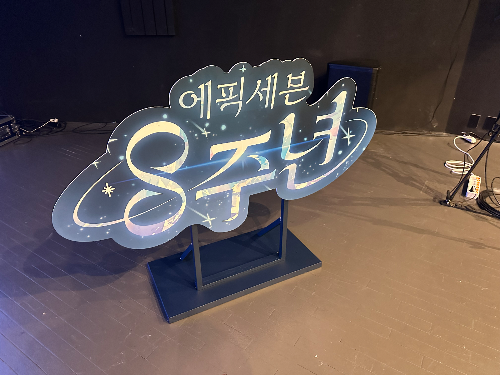 구름 모양 테두리에 '에픽세븐 8주년'이 적힌 입간판이 받침대 위에 서 있는 모습