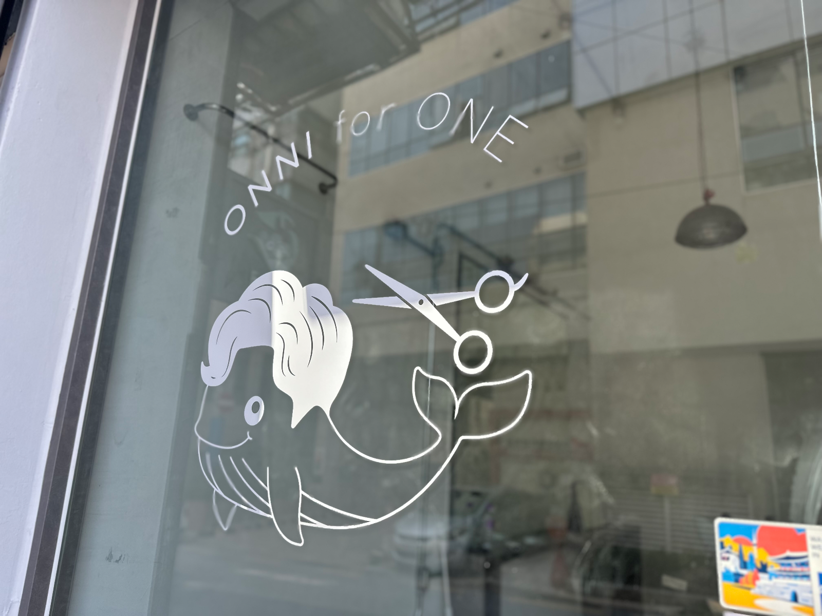유리문에 흰색 시트지로 붙은 고래와 가위 그래픽, 위쪽에 ONNI for ONE 레터링