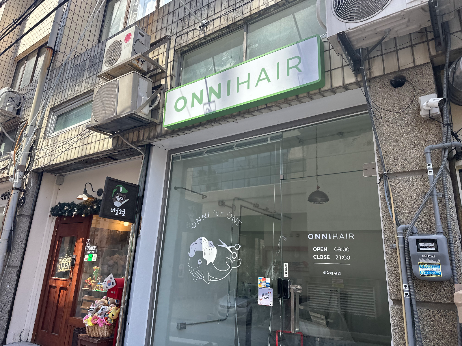 정면에서 본 온니헤어 매장. 초록 테두리 간판과 유리창 그래픽
