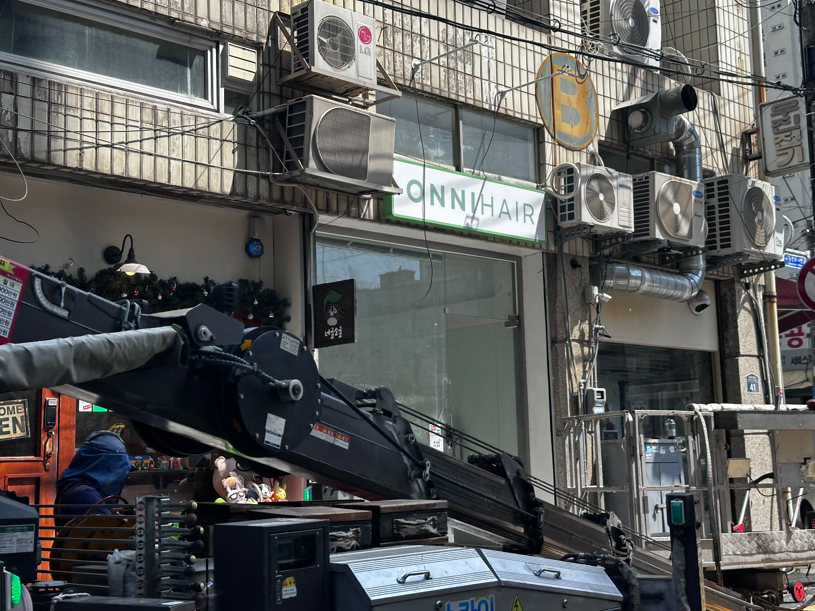 골목에서 올려다본 매장 정면과 작업 중인 고소작업차