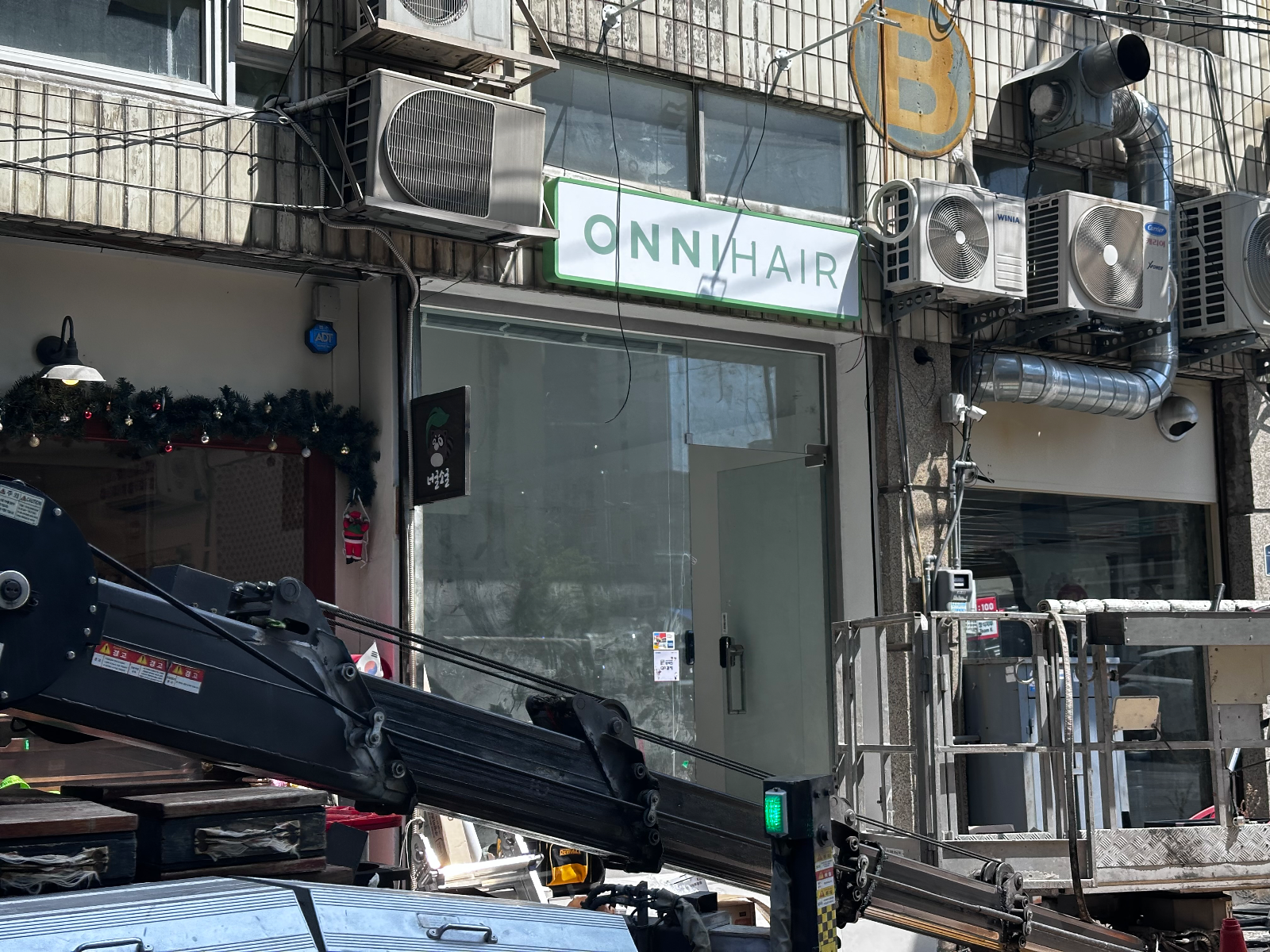 고소작업차 붐대 너머로 설치된 ONNIHAIR 간판이 보인다