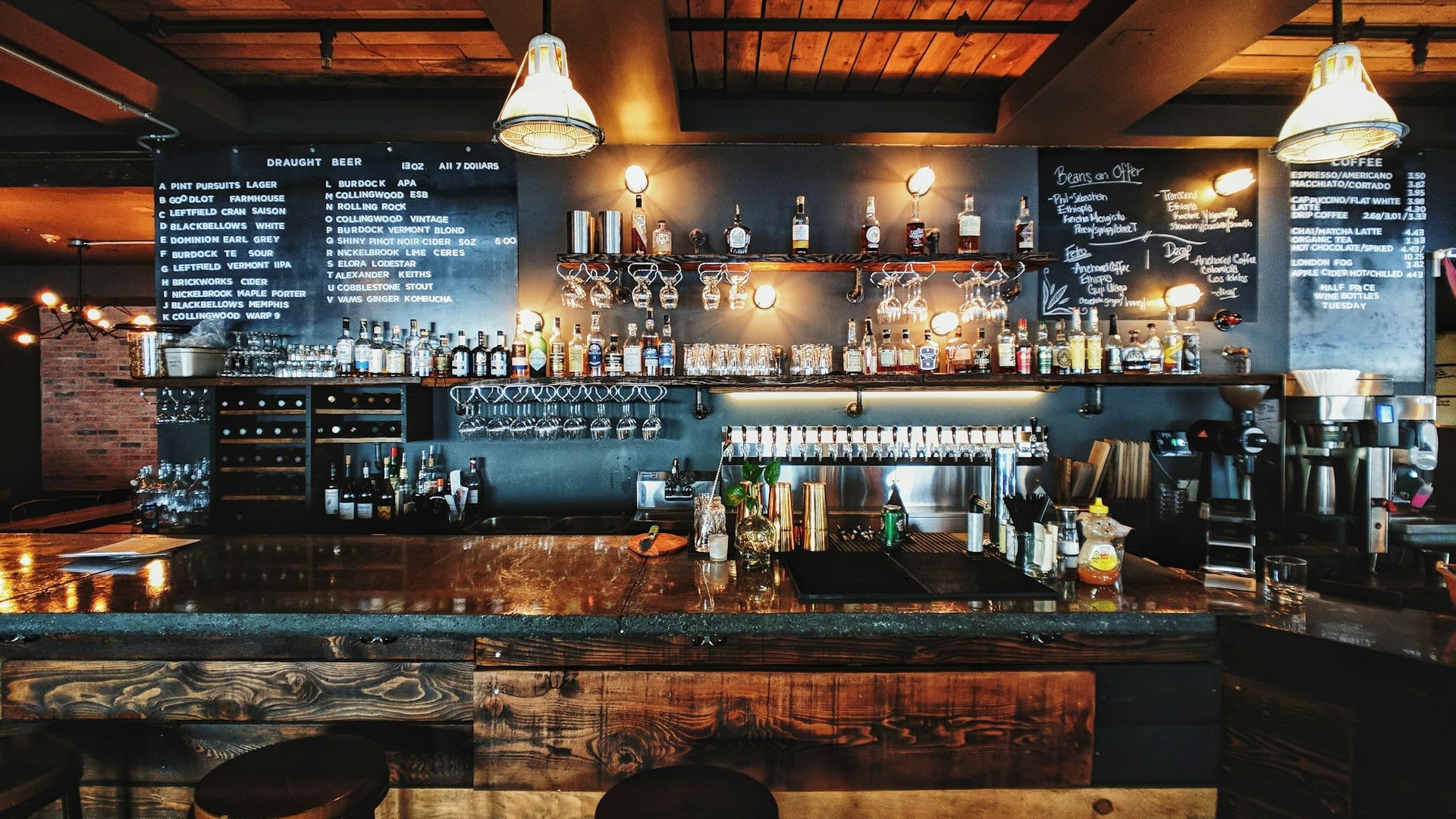 Atmospheric craft cocktail bar with backlit spirits library and warm mood illumination