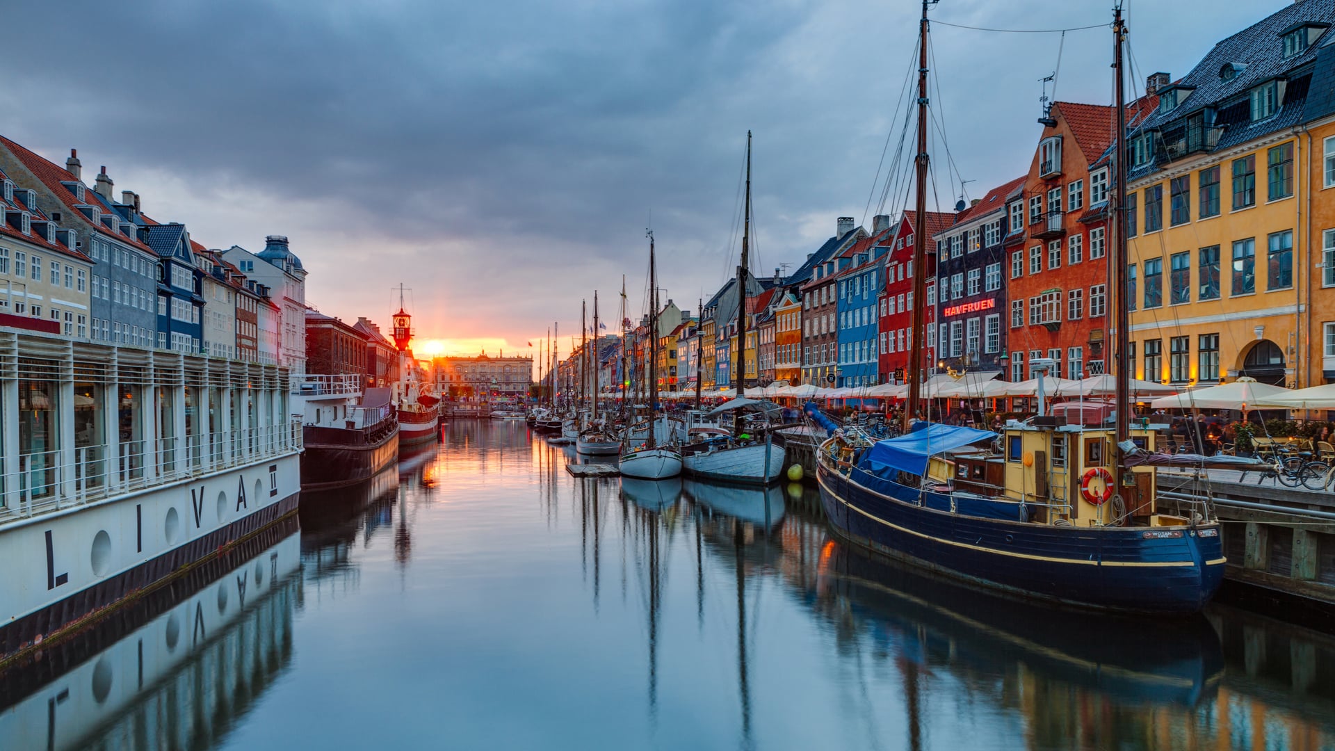 Nyhavn Copenhagen waterfront canal at sunset lined with historic townhouses and bustling outdoor cafes