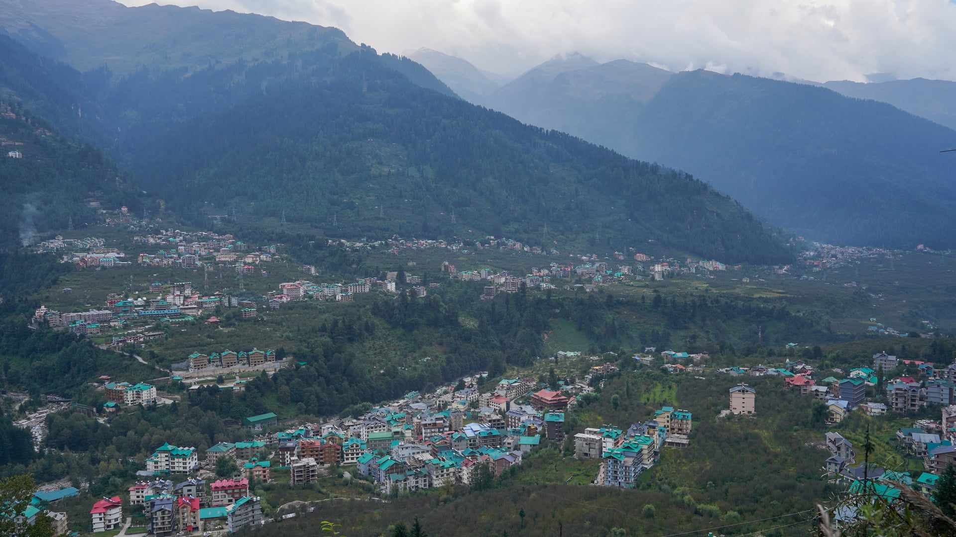 Manali valley settlement nestled beneath majestic snow-capped Himalayan peaks in Himachal Pradesh