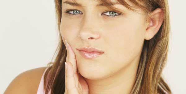 A woman holding her jaw in pain.