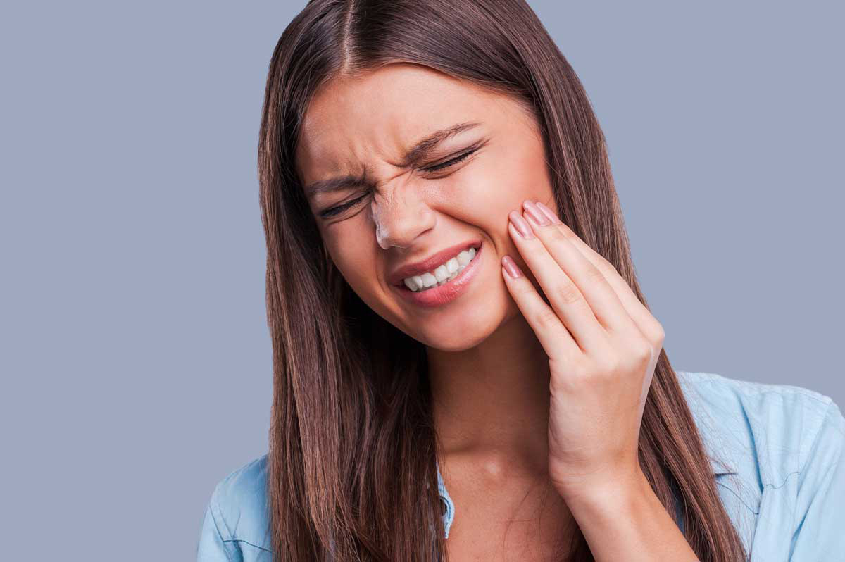 A woman holding her jaw in pain.