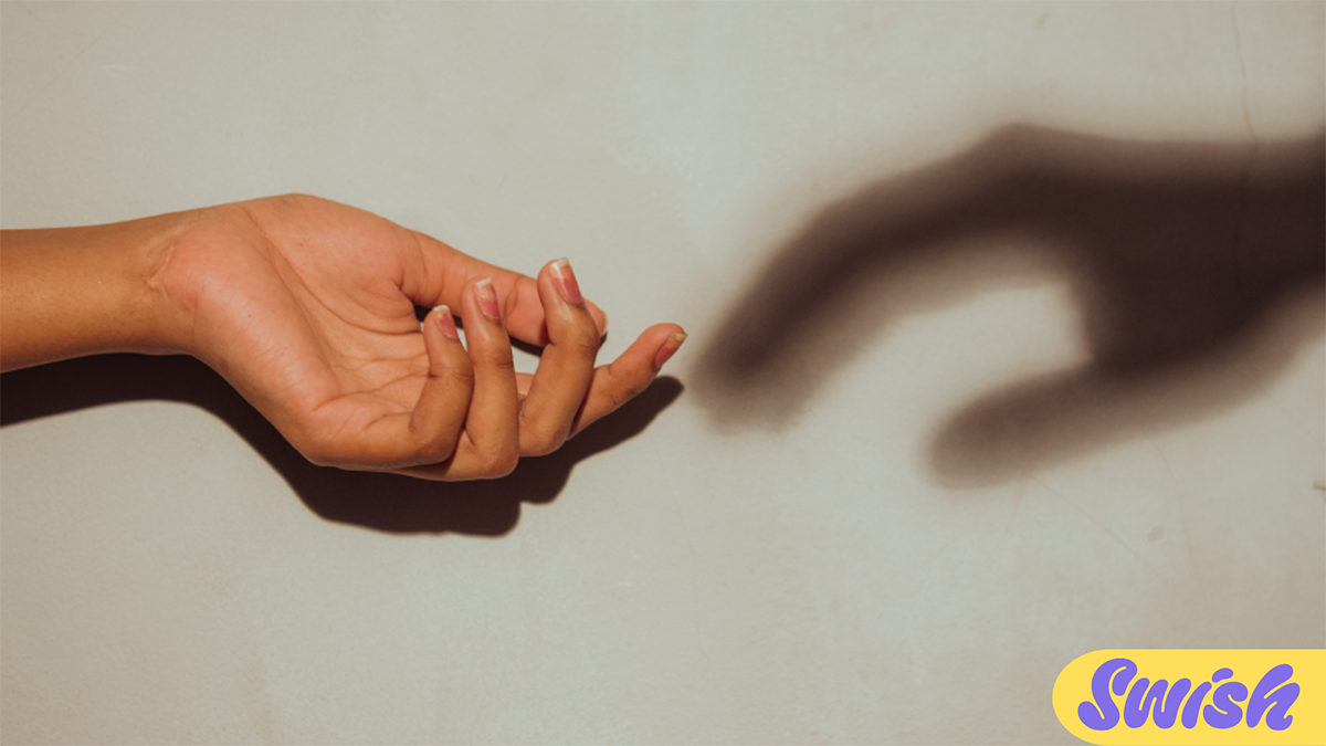 An extended hand with the shadow of another hand reach towards it.