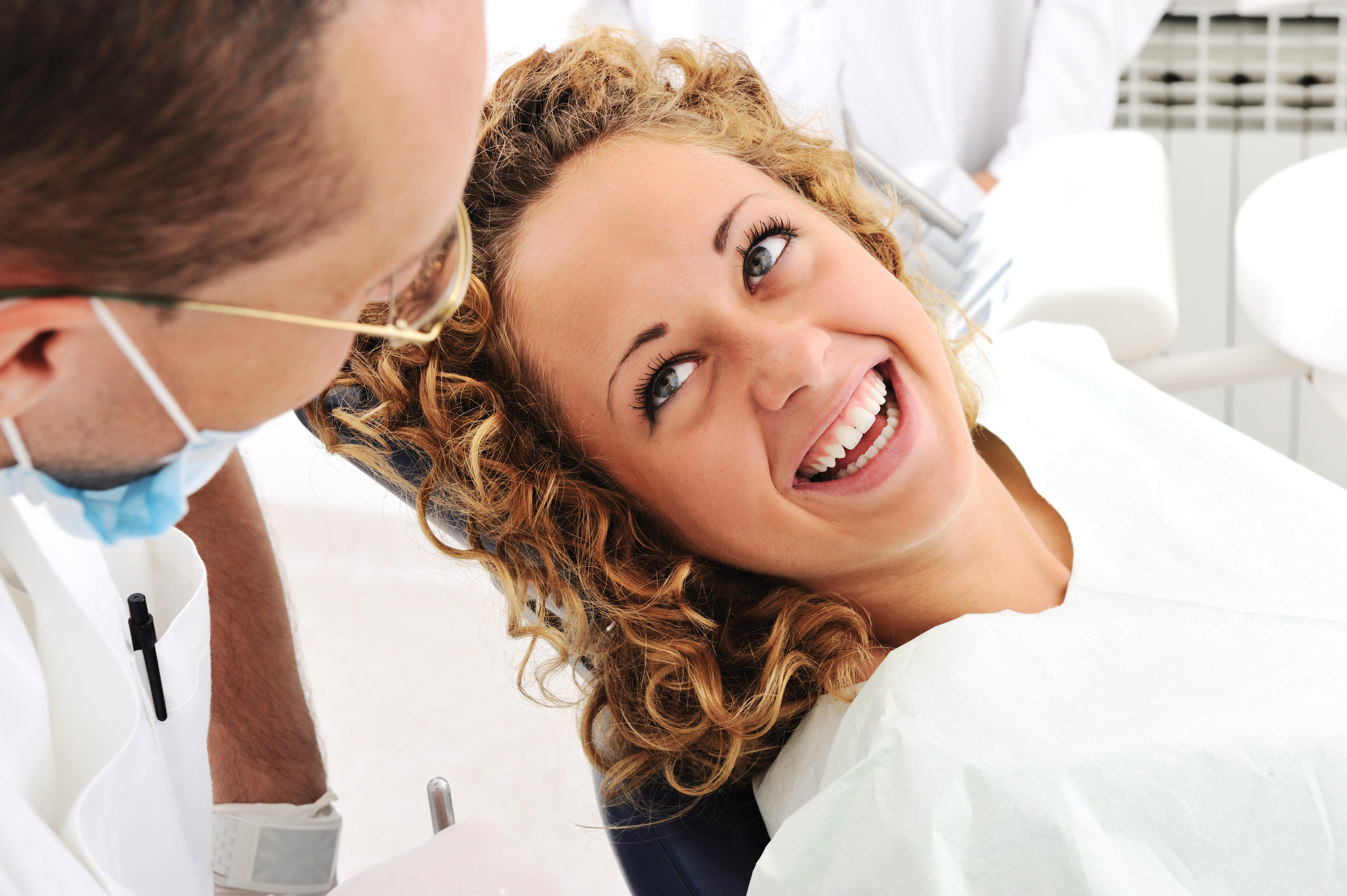 A woman laughing wheil talking with her dentist.