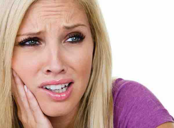 A woman holding her jaw in pain.