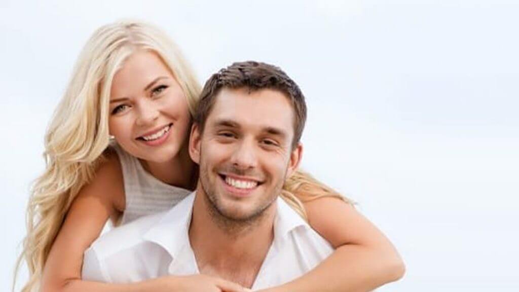 women holding man while both smile with nice teeth