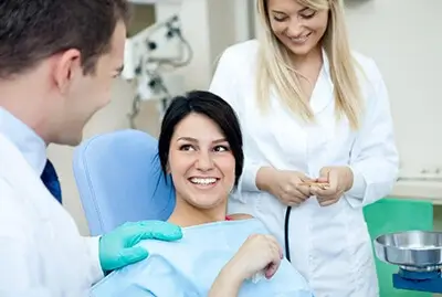 Women patient surround by two dentist conversing and smiling with nice teeth.