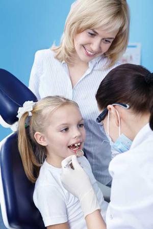 child in chair receiving dental care with parent by side