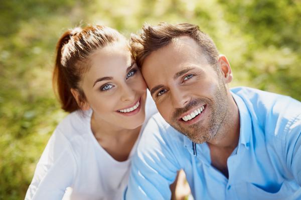 man and women resting heads on each other smiling with nice teeth 