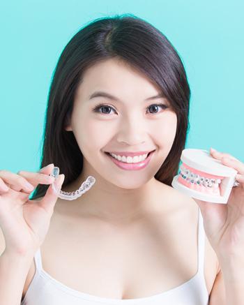 women holding Invisalign and tooth model