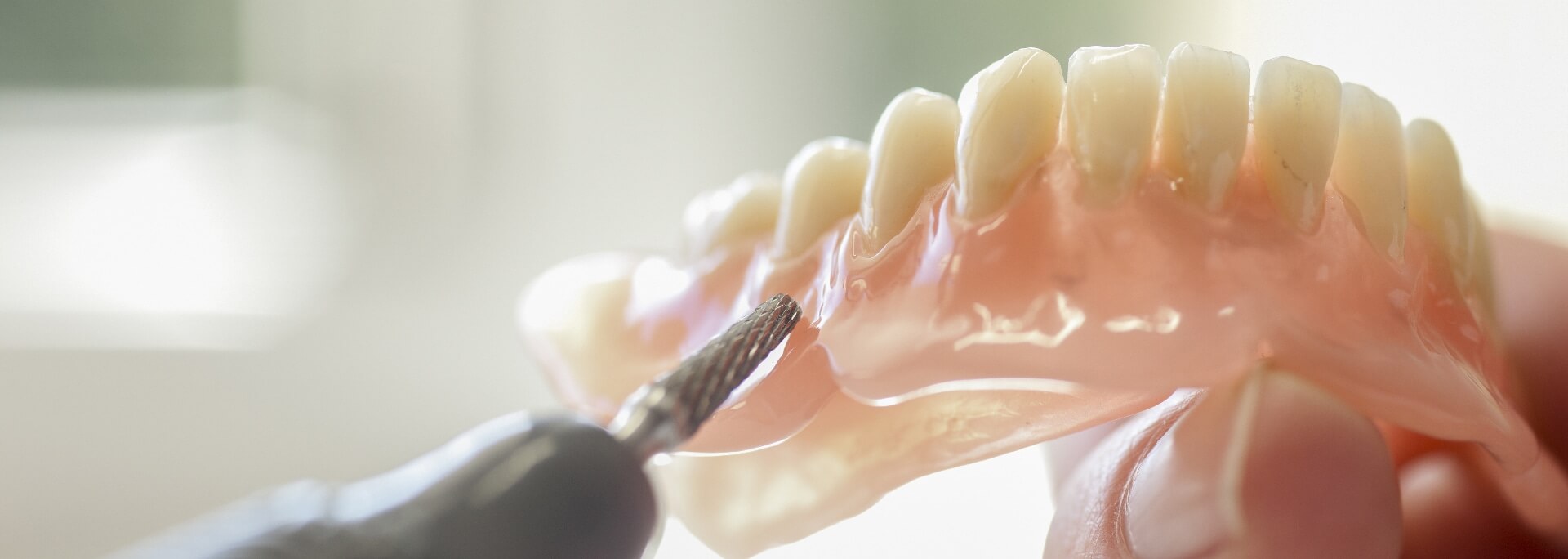 A denture tool being demonstrated on a model of teeth.