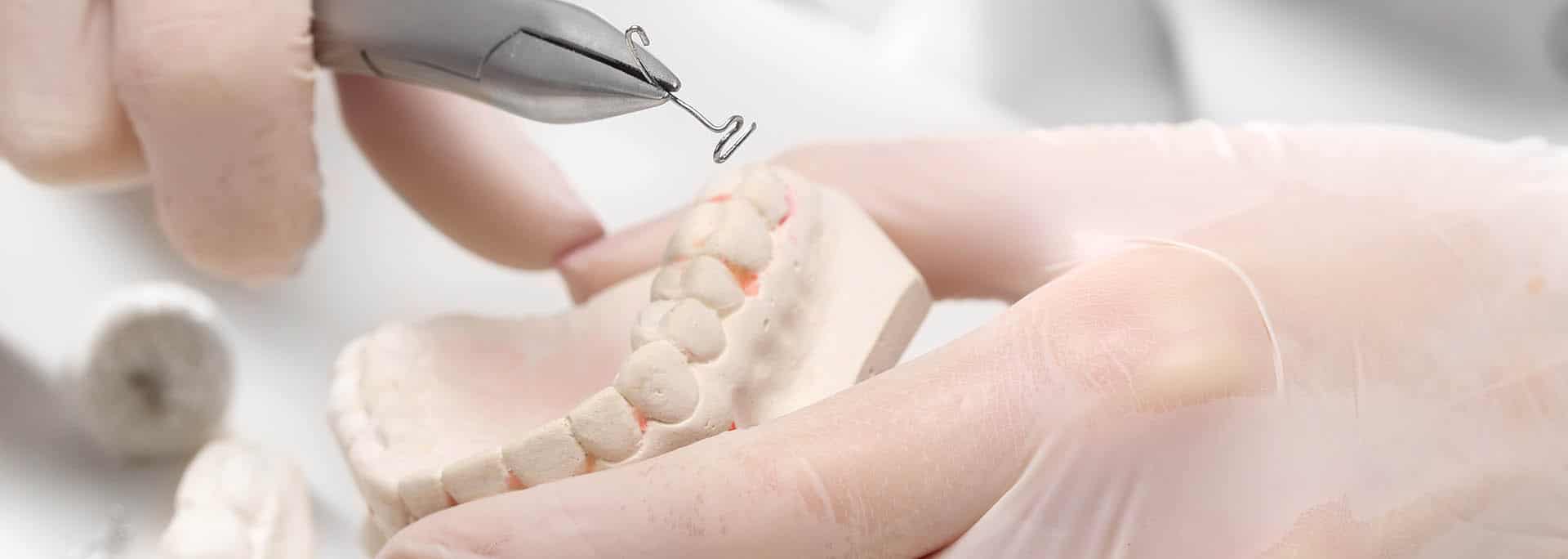 A denture tool being demonstrated on a model of teeth.