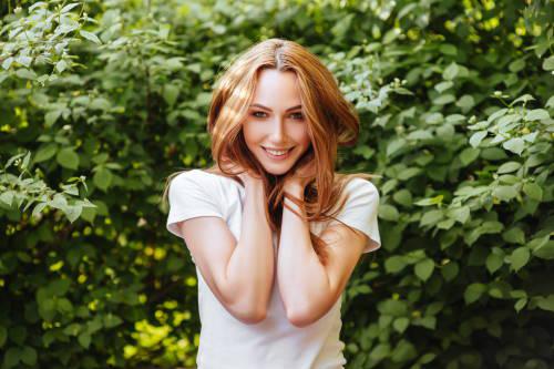 redheaded woman smiling in front of a tree