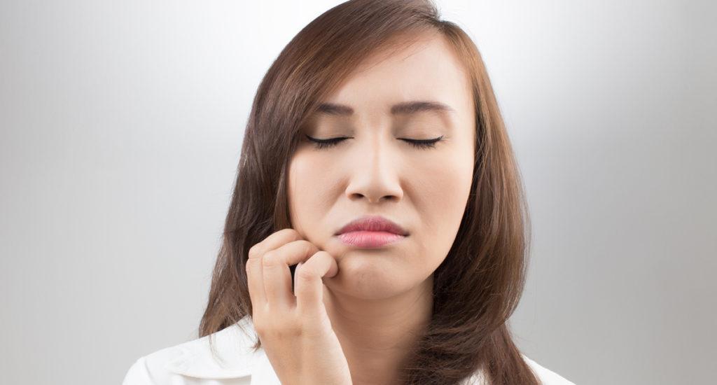 woman gripping her jaw from tmj pain