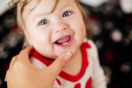 an infant showing off her two front teeth