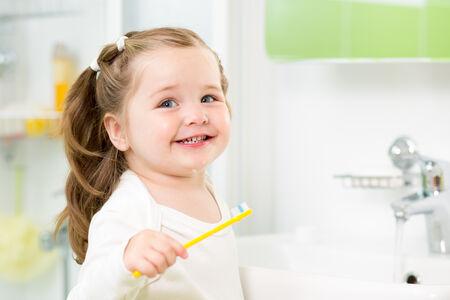 smiling young woman posing as she brushes her teeth