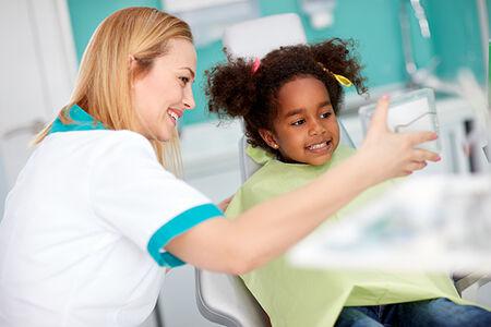 dental hygienist showing her young patient a photo of her family