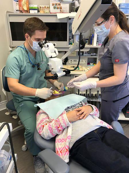 dentist operating with Prima Surgical Microscope