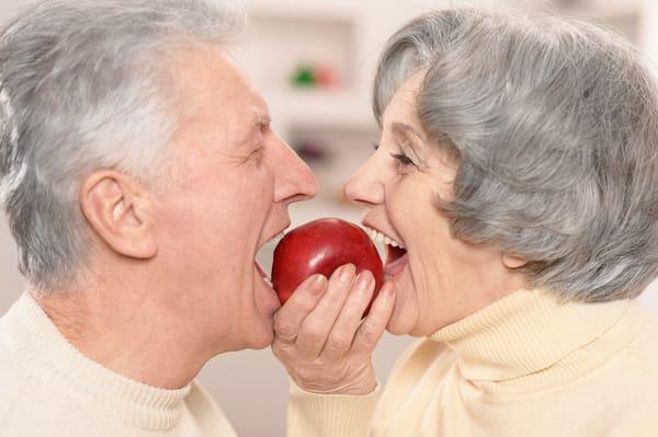 senior couple with dentures eating an apple