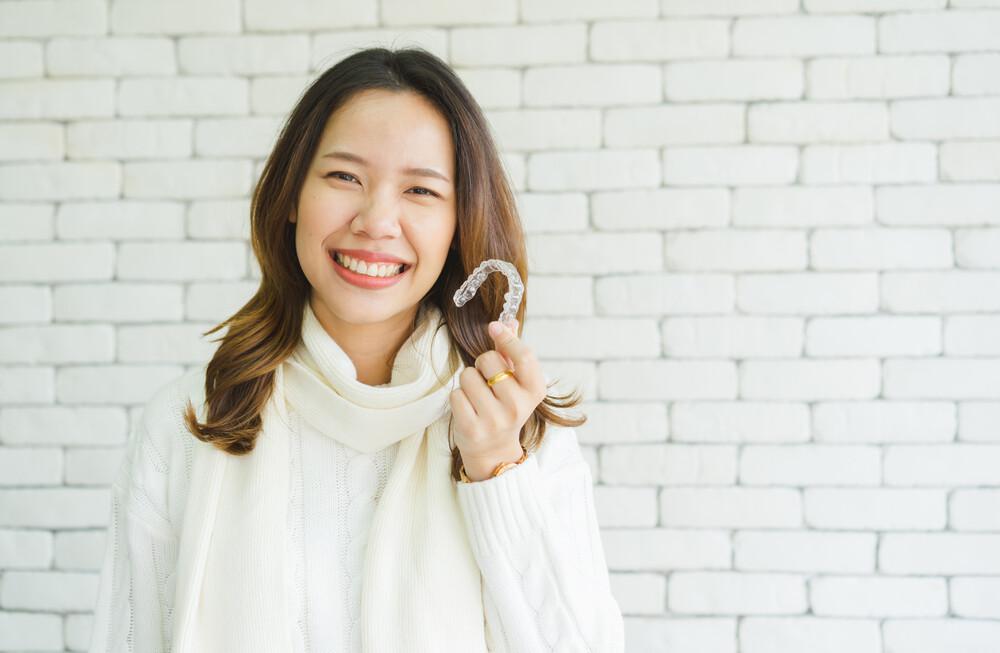 A woman holding up her Invisalign.