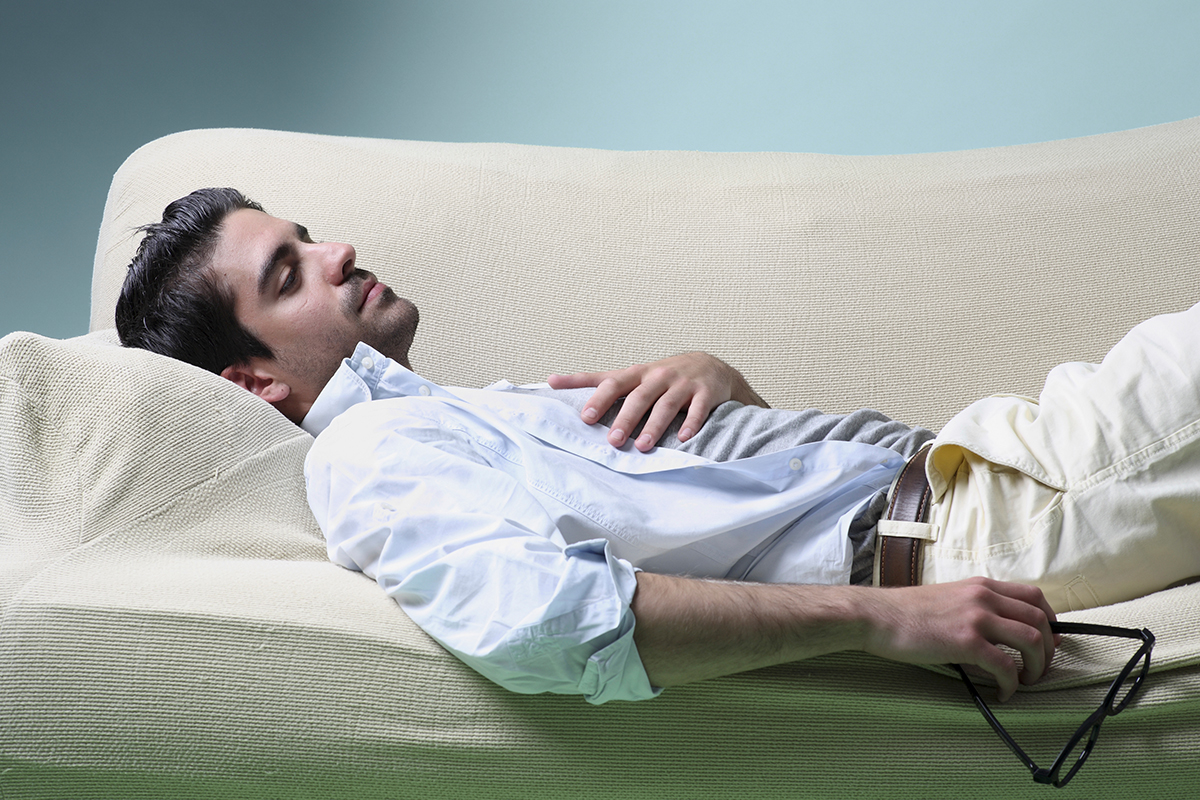 A man lying on the couch looking tired.