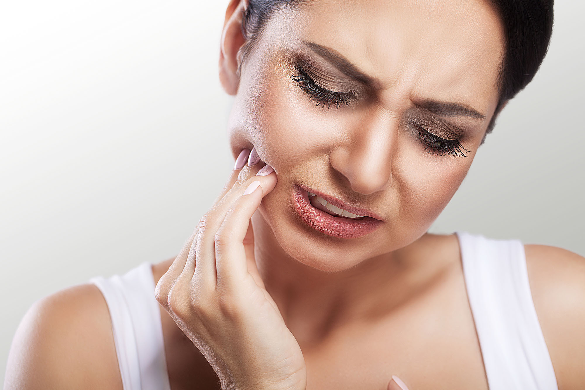 A woman holding her mouth in pain.