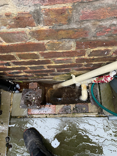 Overflowing rear gully before unblocking — water unable to drain away due to moss and fat deposits.