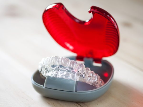 Invisalign clear aligners in a red case.