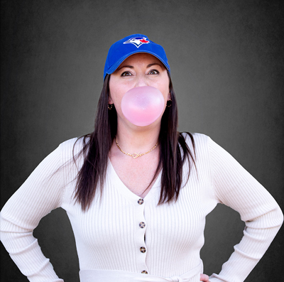 Dental Hygienist, Jill wearing a Blue Jays baseball cap and blow a big bubble with gum.