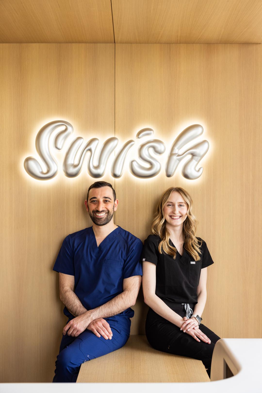 Dr. Shlah and Jaelyn Stenhouse sitting under a neon Swish logo sign and Swish Oral Care.