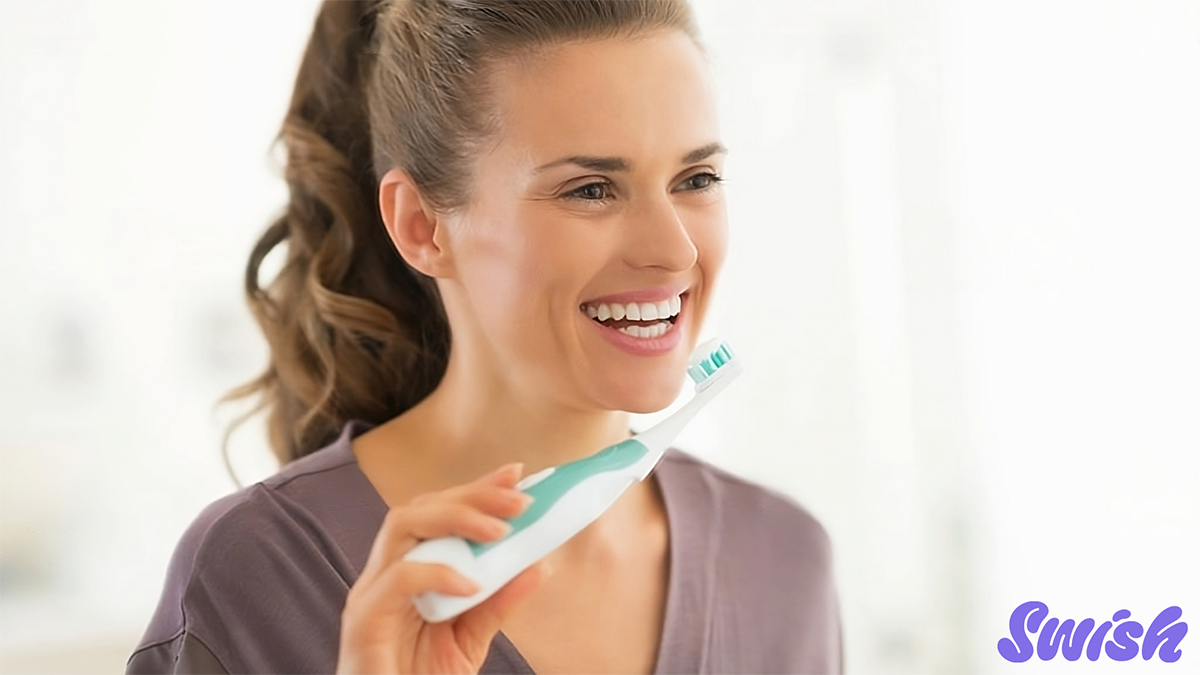 A woman smiling and holding a toothbrush.