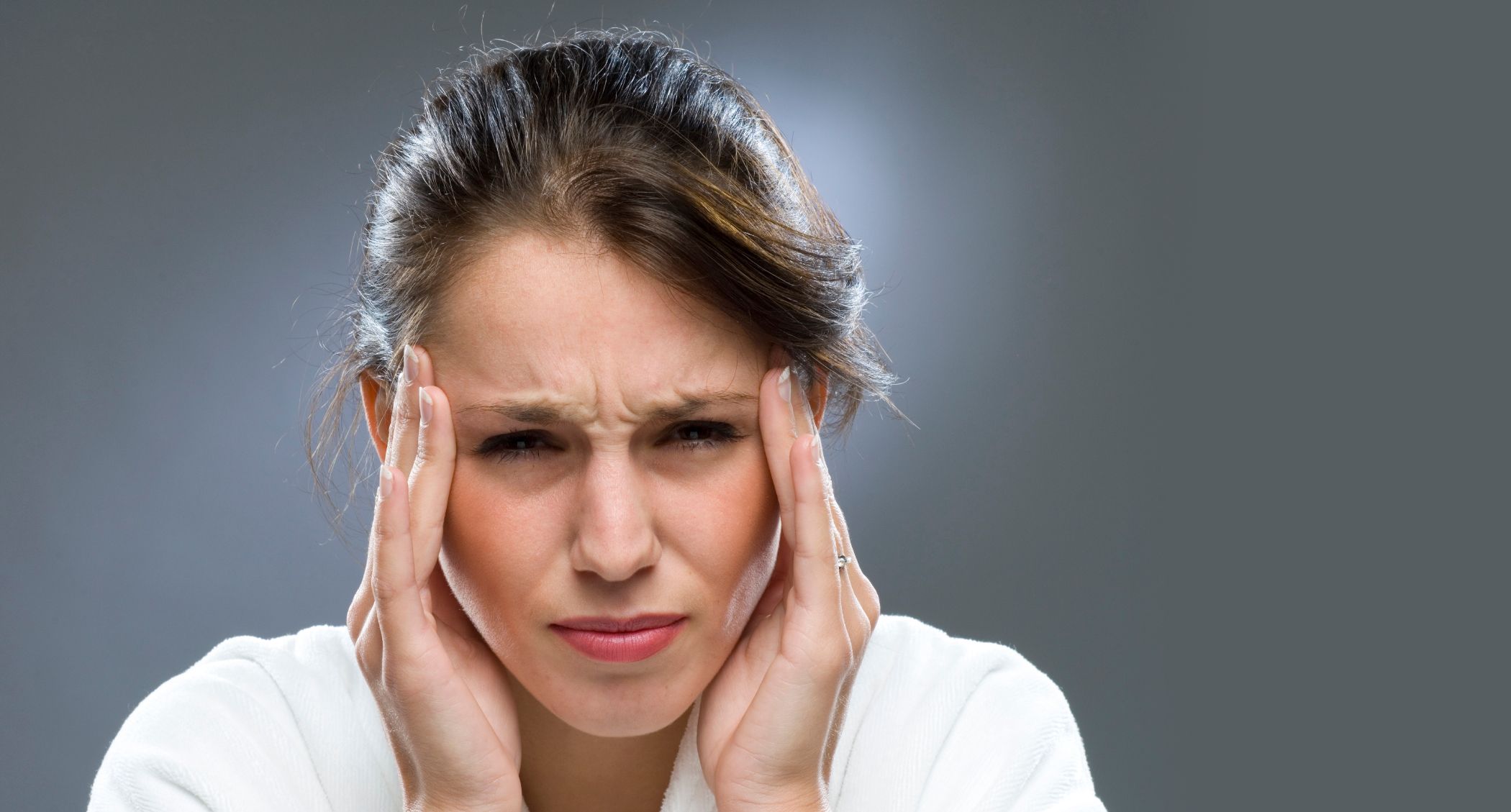 A woman holding her head in pain.