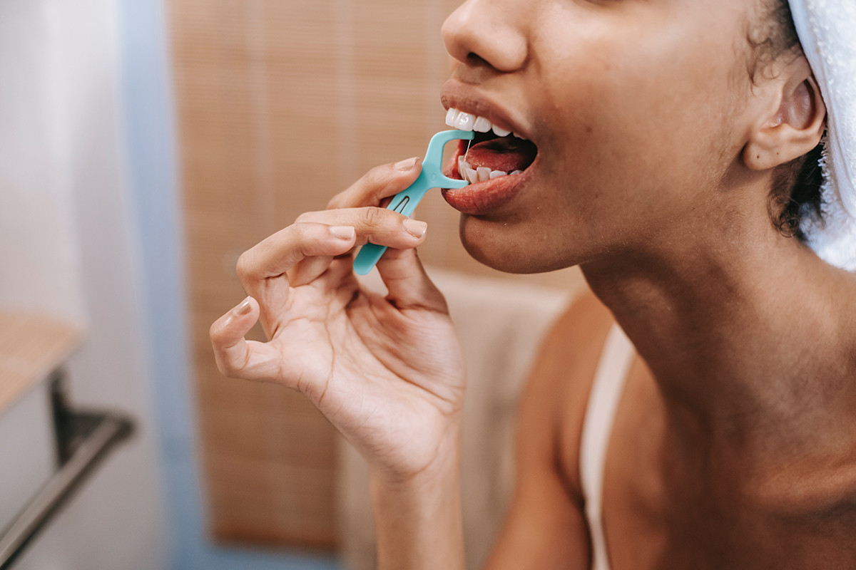 A woman flossing in the mirror.