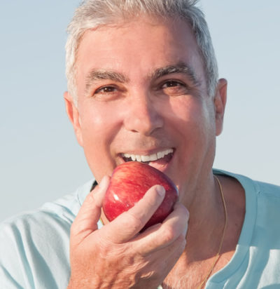 man eating an apple while wearing dentures