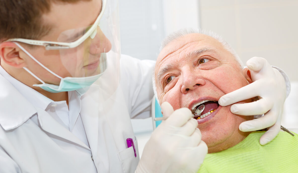 Dentist checking old person teeth