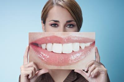 woman holding a picture of white teeth