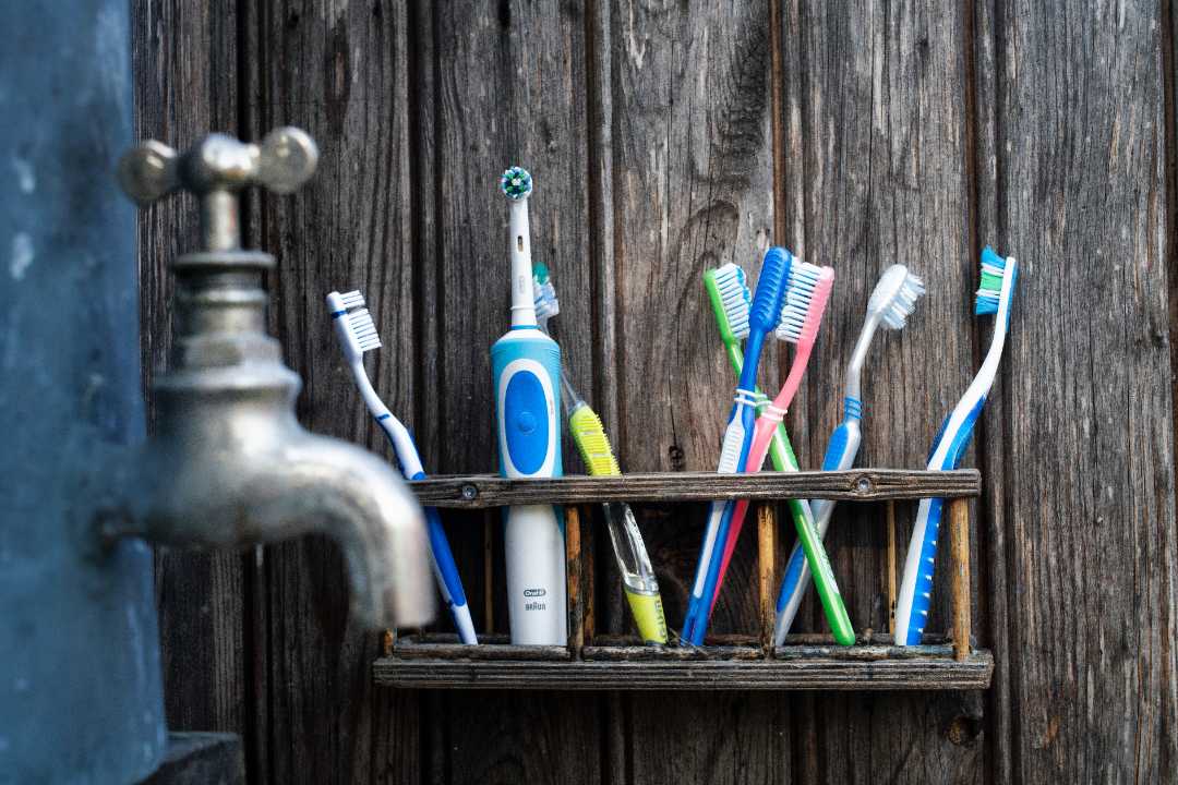 an electric toothbrush on a shelf with manual brushes 