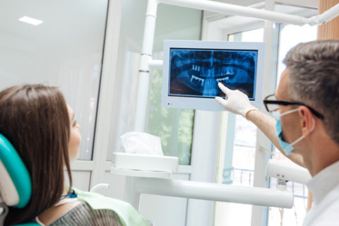 A dentist pointing at a tooth x-ray.