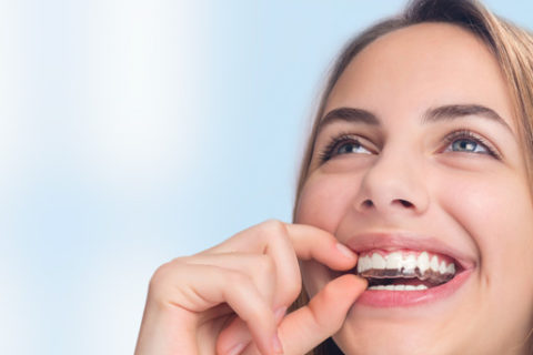 A woman smile while putting on her Invisalign.