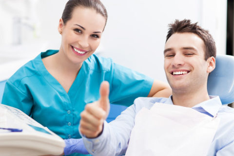 A patient giving the thumbs up with his dental hygienist.