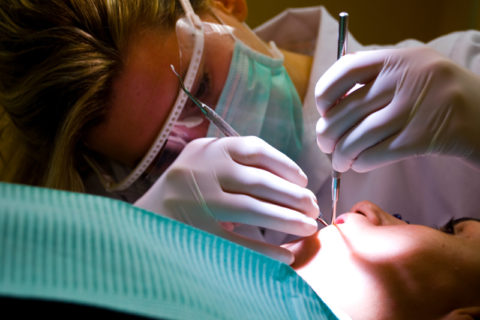 A dentist examining a patient's gums and teeth.